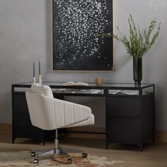 a black and white desk with an art piece on the wall in front of it