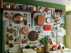 a kitchen wall covered in lots of cooking utensils and pans hanging on the wall