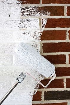 a white paint roller is being used to paint a brick wall