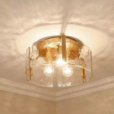 a light fixture in a room with white walls and ceiling fan on the right side