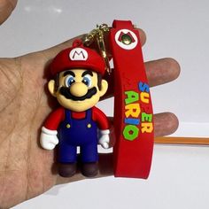 a hand holding a nintendo keychain that has a mario bros character on it