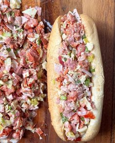 two hot dogs with toppings sitting on top of a wooden table