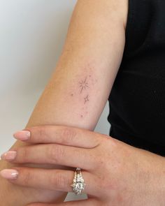 a woman's hand with a small star tattoo on her left arm and a diamond ring