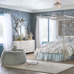 a bedroom decorated in blue and white with a four poster bed, dressers, mirror and ottoman