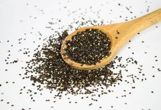 a wooden spoon filled with seeds on top of a table