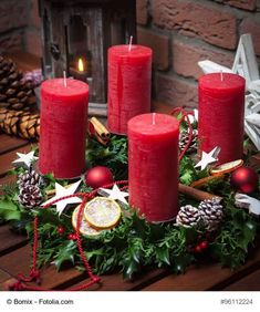 three red candles sitting on top of a table next to christmas decorations and pine cones