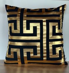 a black and gold pillow sitting on top of a wooden floor