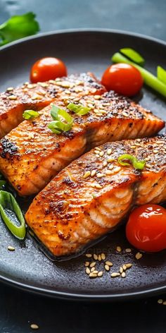 two salmon fillets on a plate with tomatoes, green beans and sesame seeds next to them