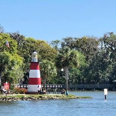 a red and white lighthouse sitting in the middle of a lake