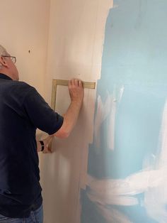 a man is painting a wall with blue and white paint