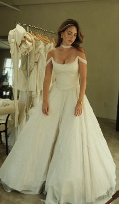 a woman standing in front of a dress hanging on a rack