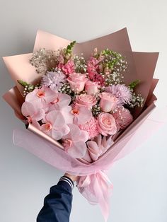 a person holding a bouquet of pink flowers