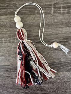 an american flag tassel hanging on a wooden surface with beads and string attached to the tassel