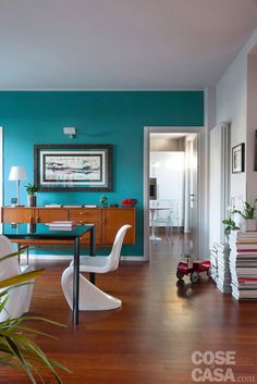 a living room with blue walls and white chairs in front of a wooden flooring area