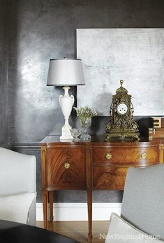 a living room with two chairs, a table and a clock on top of it