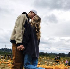 a man and woman kissing in front of pumpkins