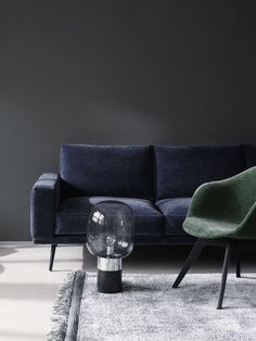 a living room with a blue couch and green chair next to a glass table on top of a rug