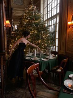 a woman in a black dress is setting a table