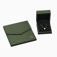 an open green box with a necklace in it and a white diamond on the inside