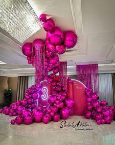 pink balloons and streamers are on display in a room