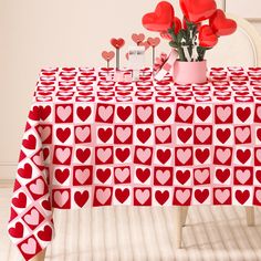 a table topped with lots of hearts covered in red and white paper next to a vase filled with flowers