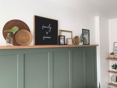 a shelf with some pictures and plants on top of it in a room that is painted green