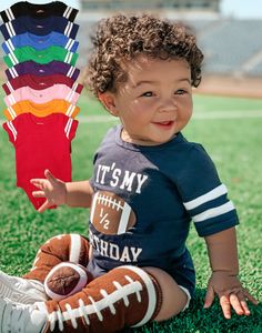 a baby sitting on the grass with football gloves