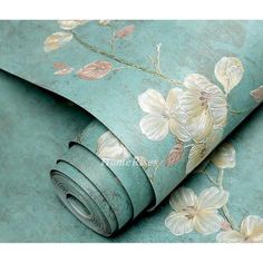 a wallpaper with flowers on it in blue and green colors, as well as a roll of tape