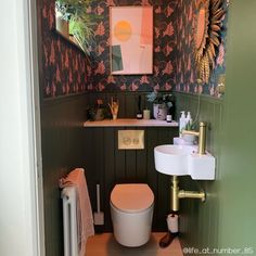 a toilet and sink in a small room with wall paper on the walls behind it