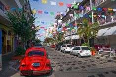 an old red car parked in front of a row of white cars on a city street