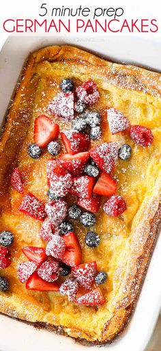 a close up of a french toast with berries on it and powdered sugar on top