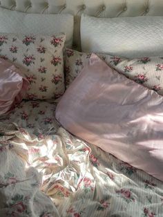 an unmade bed with pink and white sheets, pillows and blankets on top of it