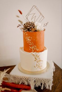 a three tiered cake with an orange and white frosting design on the top