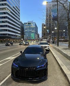 a black sports car is parked on the side of the road in front of some tall buildings