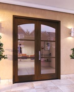 the front door to a home with two glass doors and potted plants on either side