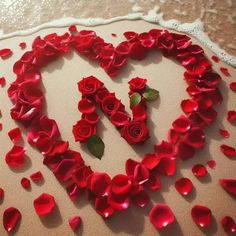 a heart made out of red roses on top of a white doily with the word love spelled in it