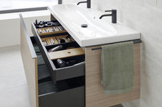 a bathroom with a sink, towel and other items in the drawer under the faucet