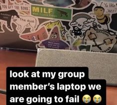 a laptop computer sitting on top of a wooden desk next to a pile of stickers