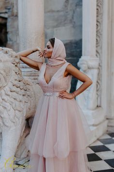 a woman in a pink dress standing next to a statue