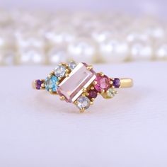 Emerald Cut Pink Sapphire Cluster Ring Multi Gemstone Engagement Ring 18K Yellow Gold Jewelry Art Deco Bridal Ring Anniversary Gift For Wife Description: Main Stone - Sapphire Stone Size - 7 x 5 MM Stone color - Pink Main Stone creation - Lab Created Stone shape - Emerald  Birthstone - September Secondary Stone - Multi Gemstone (Ruby, Aquamarine, Topaz, Amethyst) Stone Color - Multi Color Stone Shape - Round Finishing- Excellent feel free to contact me if you have any questions  Gemstone color m Elegant Yellow Gold Multi-stone Crystal Ring, Gold Cluster Ring With Gemstone Accents, Elegant Cluster Ring With Stones As Gift, Gold Multi-stone Birthstone Ring, Elegant Multicolor Cluster Ring As Gift, Elegant Multicolor Cluster Ring For Gift, Gold Multi-stone Cluster Promise Ring, Gold Multi-stone Birthstone Open Ring, Gold Multi-stone Topaz Ring