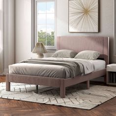 a bed sitting on top of a hard wood floor next to a lamp and window