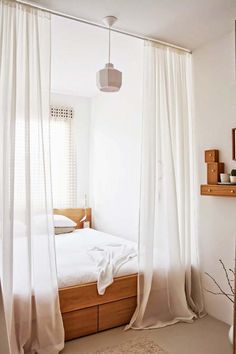 a white bedroom with sheer curtains hanging from the ceiling