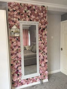 a large mirror sitting on top of a wall covered in pink and white flowers next to a couch