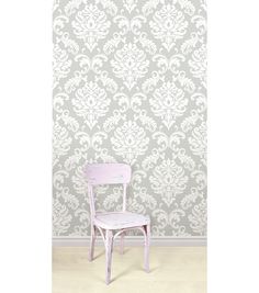 a white chair sitting in front of a wall with a pattern on the wall behind it