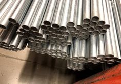 many metal pipes are stacked on top of each other