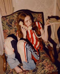 a woman sitting in a chair while talking on the phone