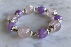 "Genuine gemstone bracelet - limited quantity, will not have any more available after this. Stunning custom, handmade bracelet with large, light rose quartz beads and slightly smaller purple kunzite beads. Silver-toned accents. Gorgeous and shiny -- really catches the light well.  Bracelet can stretch to fit your wrist. In its \"resting,\" un-stretched state, it is around 7.5 inches in circumference. Length is around 8 inches. Thickness of round beads is about 13 mm or 1/2 of an inch. \"Rose Quartz purifies and opens the heart at all levels to promote love, self-love, friendship, deep inner healing and feelings of peace. Calming and reassuring, it helps to comfort in times of grief. Rose Quartz dispels negativity and protects against environmental pollution, replacing it with loving vibes. Pink Amethyst Crystal Bracelet With Gemstone Beads, Pink Amethyst Gemstone Beads Crystal Bracelet, Pink Amethyst Gemstone Beads Bracelet, Spiritual Pink Amethyst Beaded Bracelet, Pink Amethyst Beaded Bracelets For Gift, Spiritual Pink Amethyst Bracelets, Pink Amethyst Round Beads Crystal Bracelet, Pink Amethyst Beaded Bracelets With Natural Stones, Pink Amethyst Crystal Bracelet With Round Beads