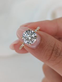 a woman's hand holding an engagement ring with a diamond on the top and side