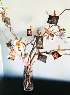 a vase filled with branches and pictures hanging from them