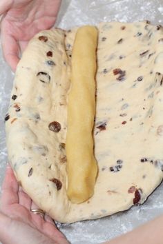 two hands are holding a dough with a long piece of bread on it